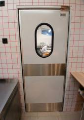 Маятниковая дверь одностворчатая МДО(ОН)-890.2100 рама внутри проема,овальное окно,отбойники Маятниковая дверь одностворчатая МДО(ОН)-890.2100 рама внутри проема,овальное окно,отбойники